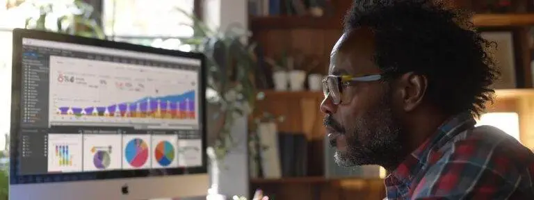 a focused man studying a computer screen displaying a search ranking monitoring tool.