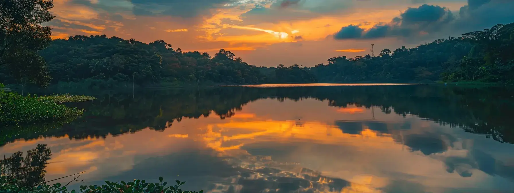 a vibrant sunset casts a warm golden hue over a serene lake, reflecting the colorful sky and surrounded by lush greenery, evoking a sense of peace and tranquility.